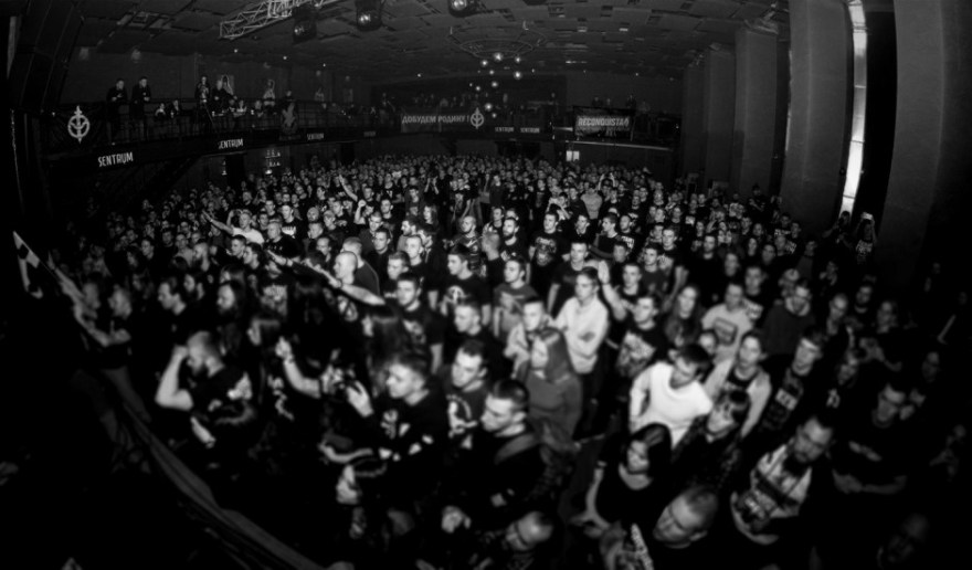 Imagen del Asgardsrei V, con parte de los asistentes realizando el saludo nazi. Al fondo a la derecha, pancarta de Reconquista. A la izquierda, el emblema del Russki Tsenter, el Centro Ruso ultraderechista en Ucrania